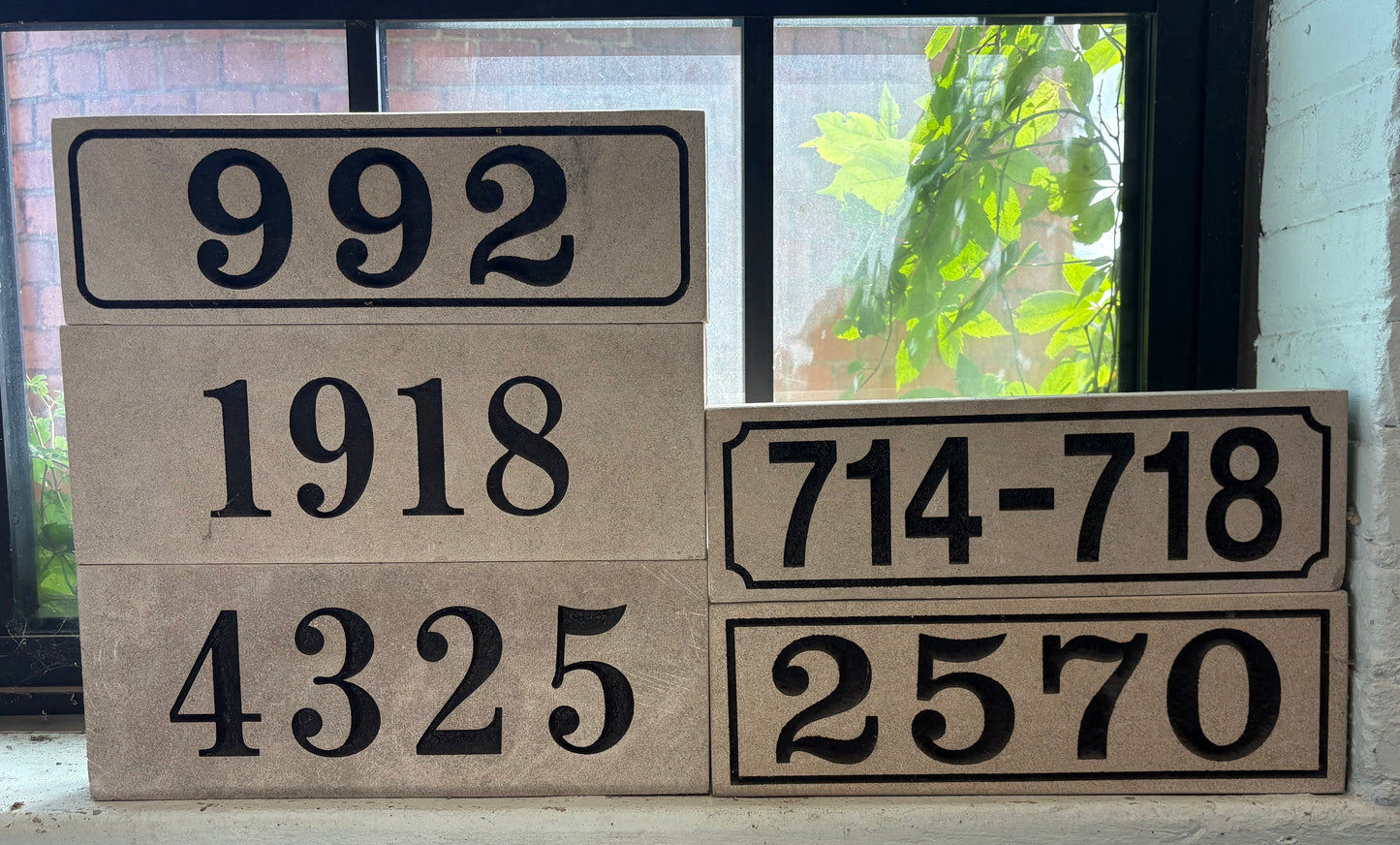A set of limestone house number stones displayed in front of a window.